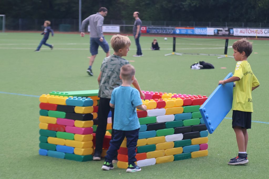 Kinder des TUS Sennelager spielen mit robusten XXL-Funblocks. Sie nutzen die großen Steckbausteine als Hürden und Parcours-Elemente beim Kindertraining und zeigen, wie vielseitig die stabilen Stapelsteine im Sport eingesetzt werden können.