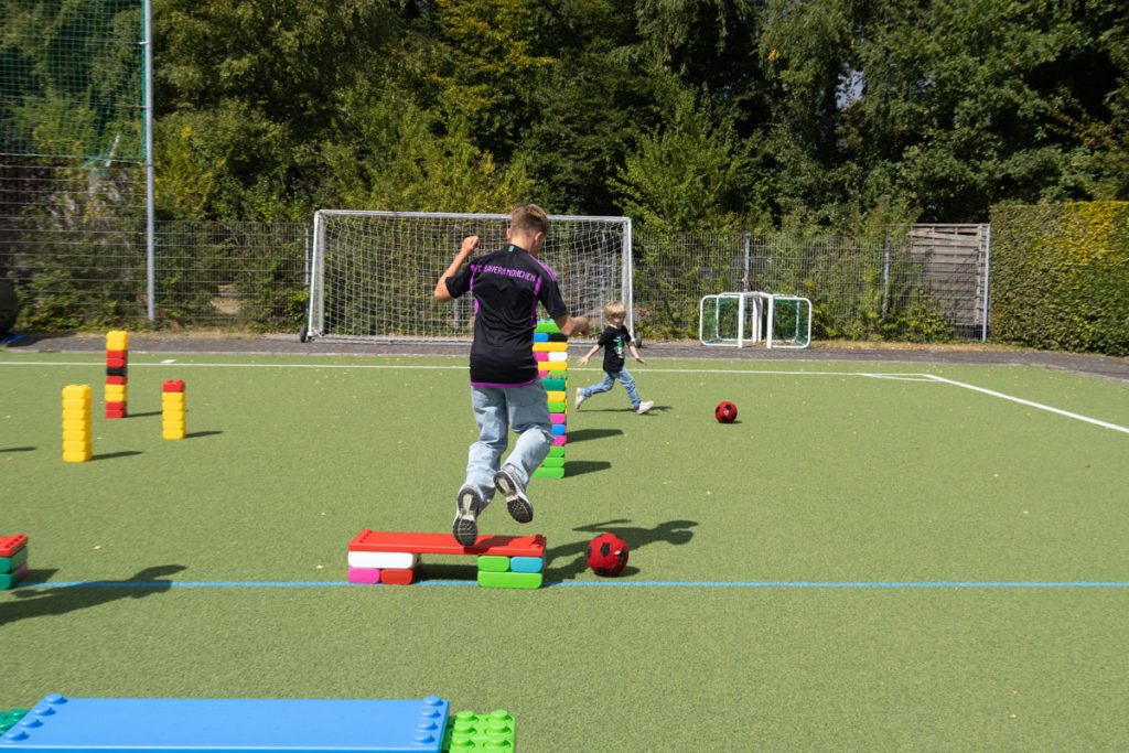 Kinder des TUS Sennelager spielen mit robusten XXL-Funblocks. Sie nutzen die großen Steckbausteine als Hürden und Parcours-Elemente beim Kindertraining und zeigen, wie vielseitig die stabilen Stapelsteine im Sport eingesetzt werden können.