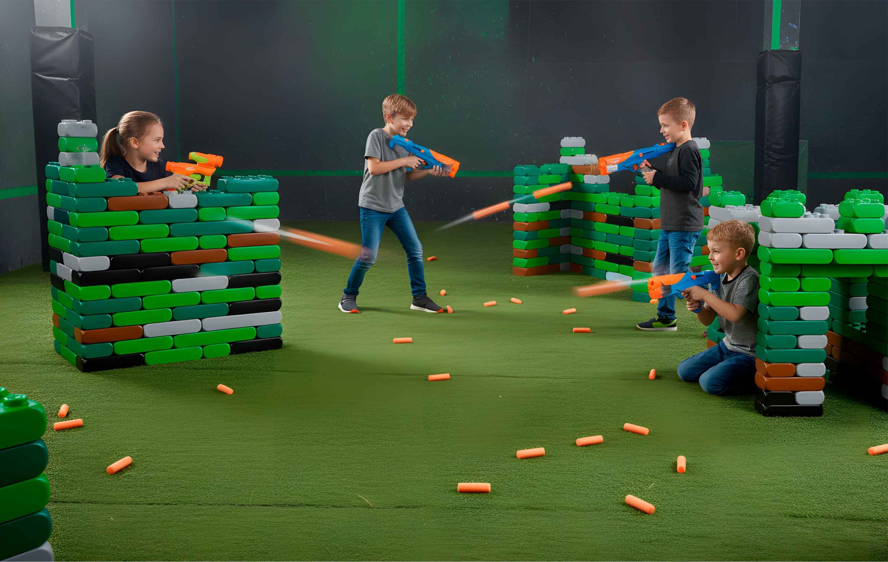 Vier Kinder spielen in einer Arena mit Nerf Guns und Hindernissen aus Spielbausteinen gegeneinander