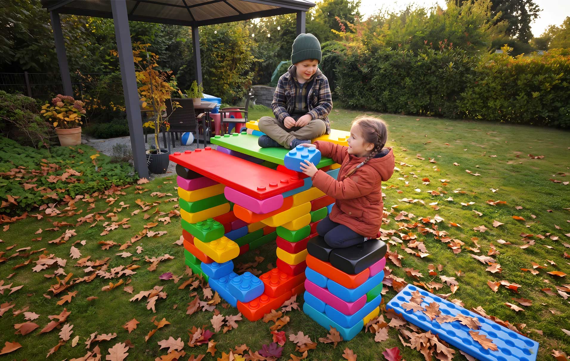 zwei Kinder spielen mit XXL Spielbausteinen im Garten im Herbst