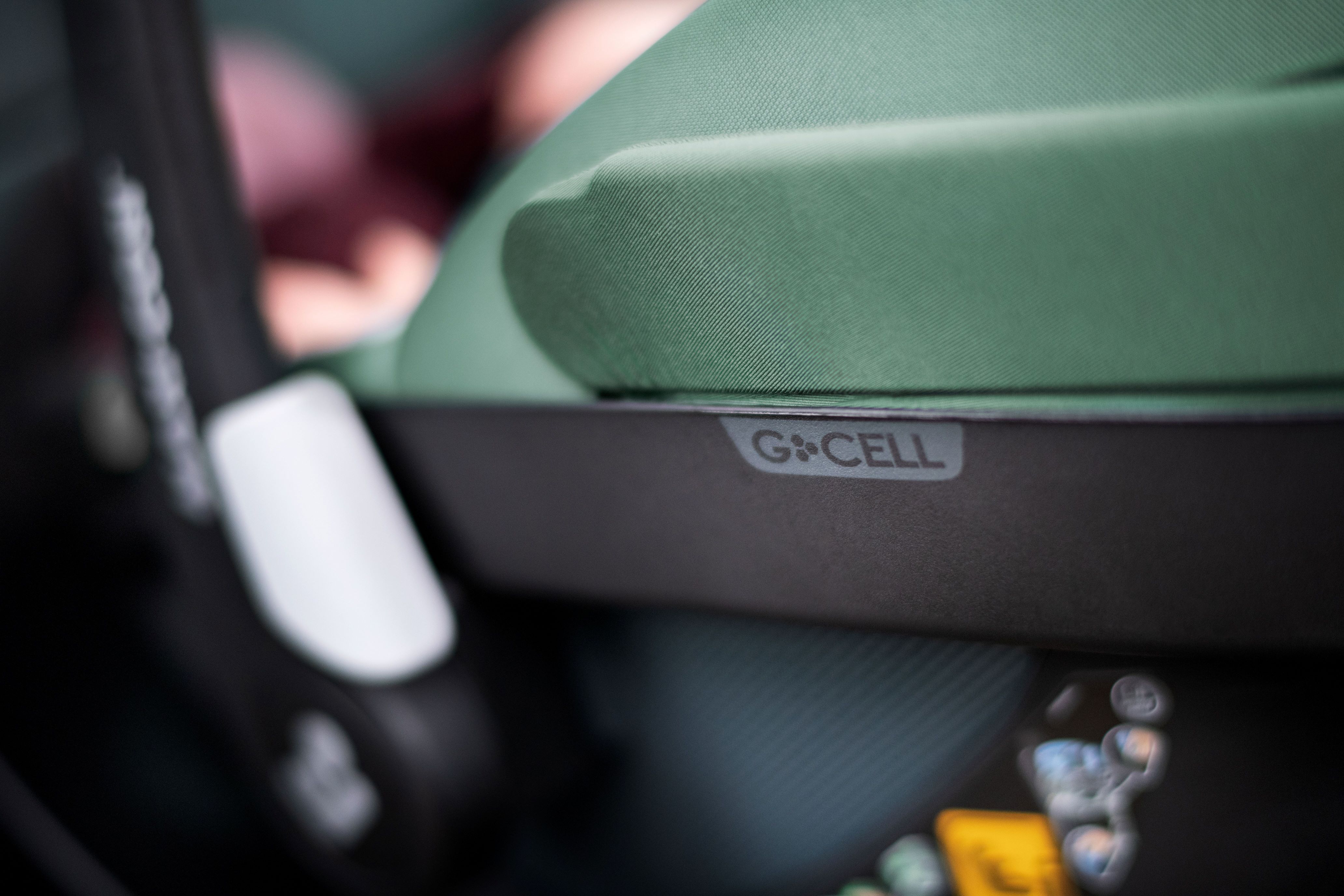 image Nahaufnahme einer grünen Maxi-Cosi Babyschale mit Fokus auf das seitlich angebrachte „G-CELL“-Label, das für besonderen Seitenaufprallschutz steht.